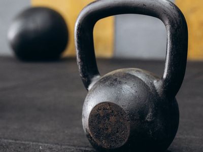 Row of heavy black kettlebells on a dark gym floor
